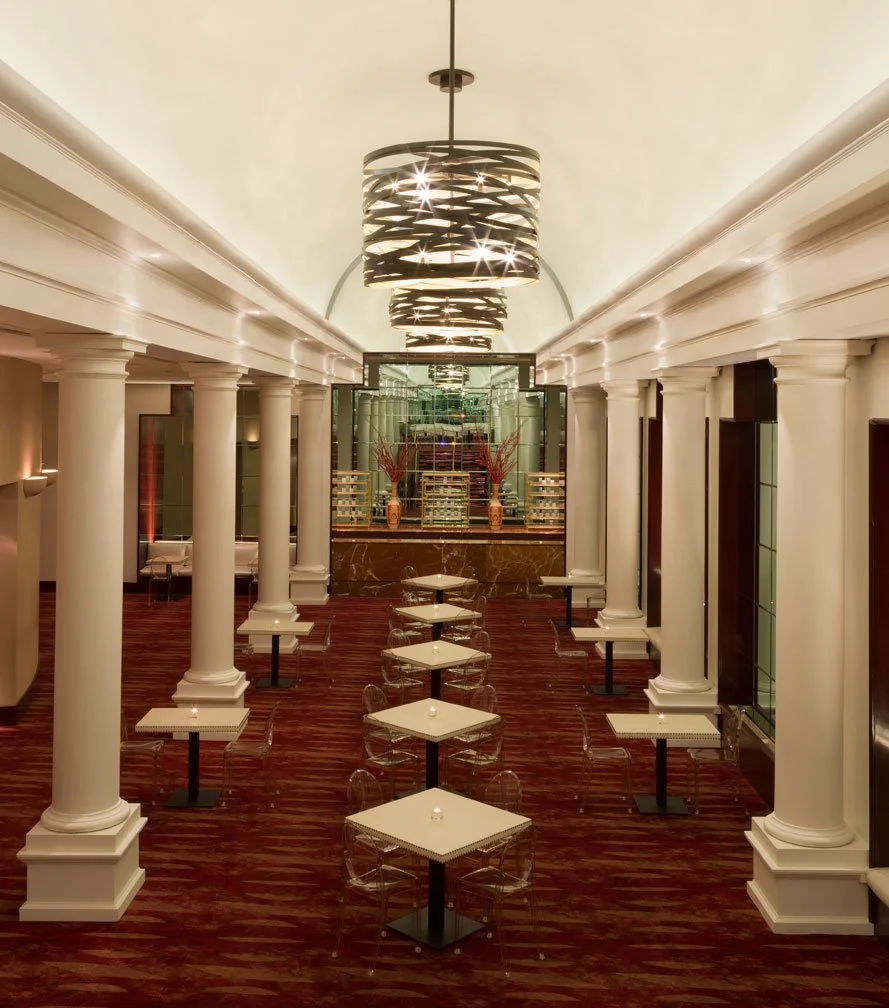 Luxury hospitality lobby illustrating commercial interior design in Houston’s Uptown Galleria district, with classical columns, dramatic lighting, and polished seating layout.