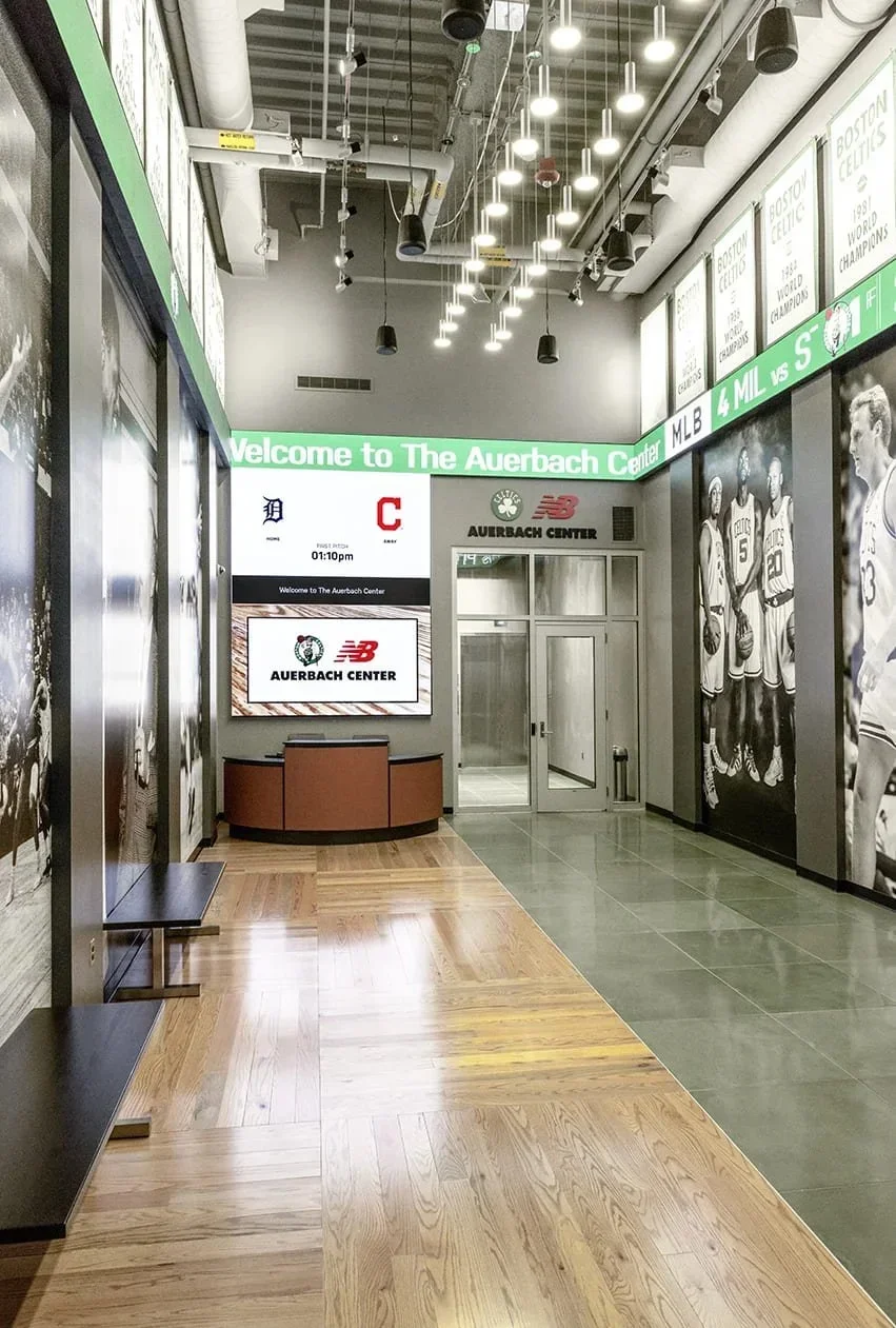 Sports facility interior design with branded graphics, digital displays and wayfinding in a commercial corridor