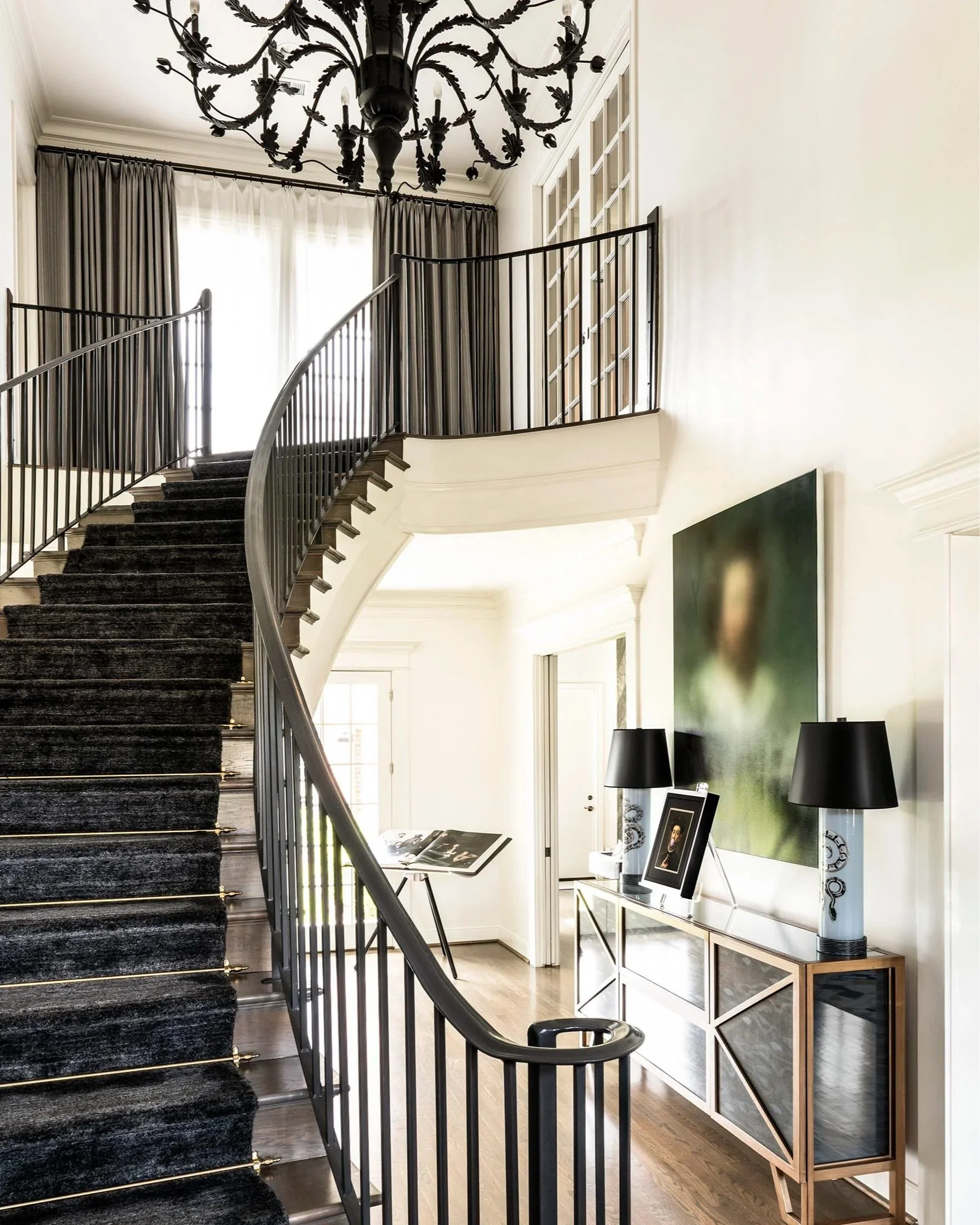 Luxury Houston entry staircase with dramatic chandelier, art display, and black stair runner at Pastureview residence.