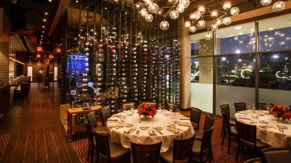 Houston restaurant interior design at Vallone’s featuring glass wine room, ambient lighting, and upscale dining atmosphere.