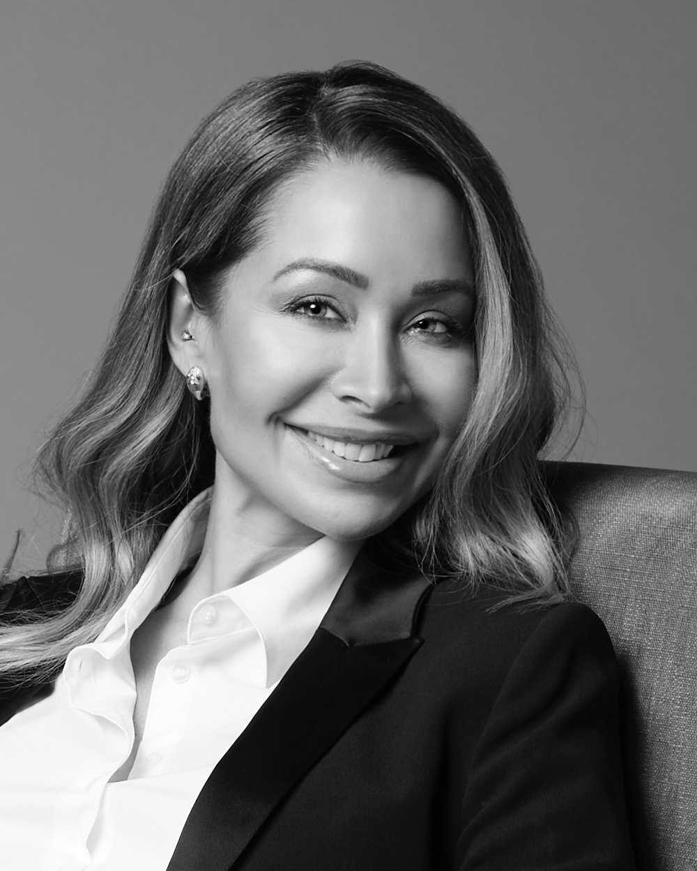 Black and white portrait of a smiling woman with long hair wearing a blazer and a white shirt.