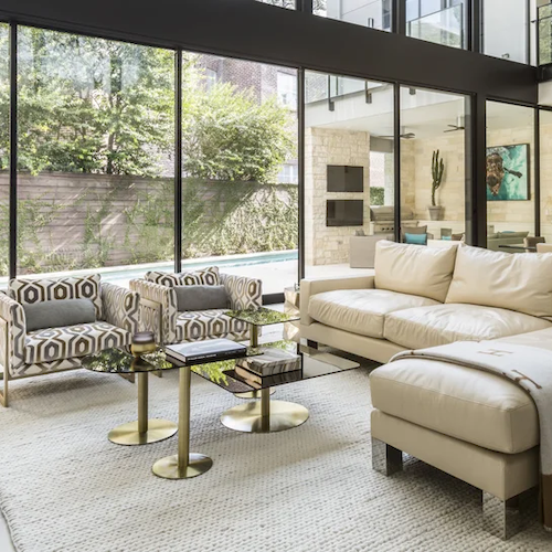 Full service interior design in Houston featuring a modern living room with floor-to-ceiling glazing and layered neutral furnishings