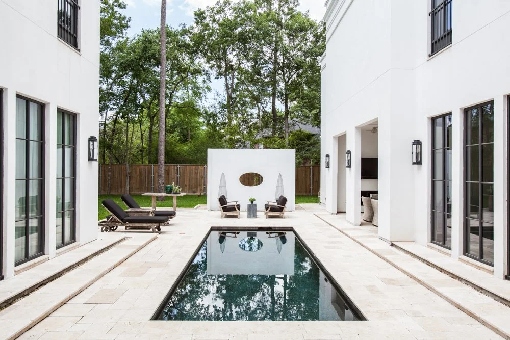 Luxury residential interior design extending to a modern pool courtyard with outdoor lounge areas and a calm architectural finish