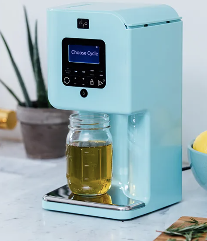 A blue appliance with a "Choose Cycle" display, dispensing liquid into a glass jar on a counter.