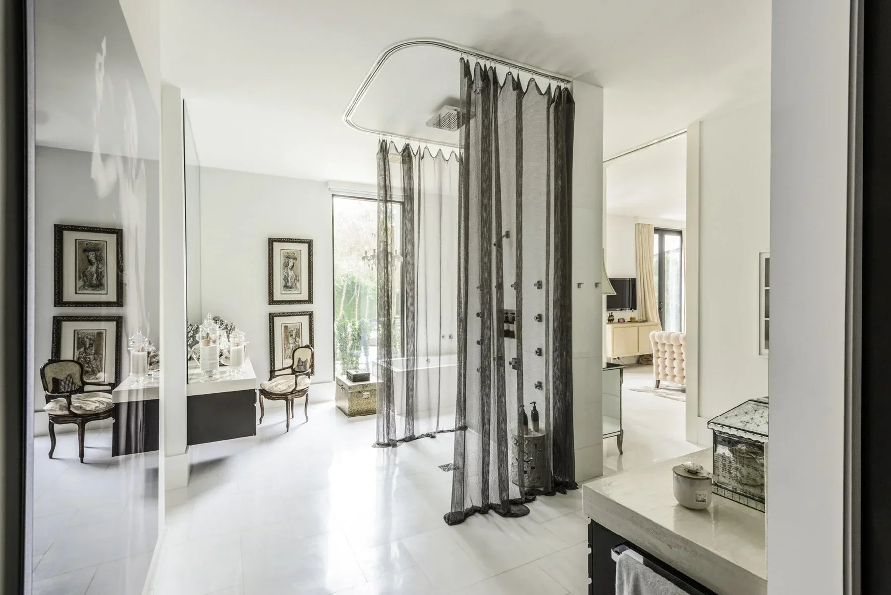 Luxury residential interior design with an open-plan bathroom and dressing space, featuring a sculptural shower, curated furnishings, and a refined spa-like feel
